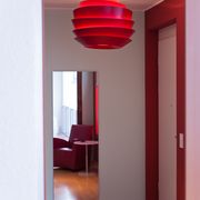 Rote Deckenleuchte in einem Raum mit roter Wand, Spiegel und rotem Sessel
