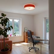 Rote Deckenleuchte in einem Büro mit Sessel und Glasschreibtisch